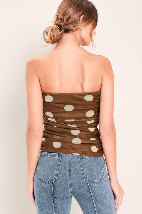 Woman wearing a brown strapless power mesh top with white polka dots and side shirring | Flying Tomato