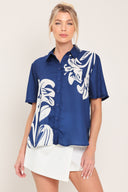 Woman wearing a navy blue with white floral print collared, short-sleeve button down top | Flying Tomato