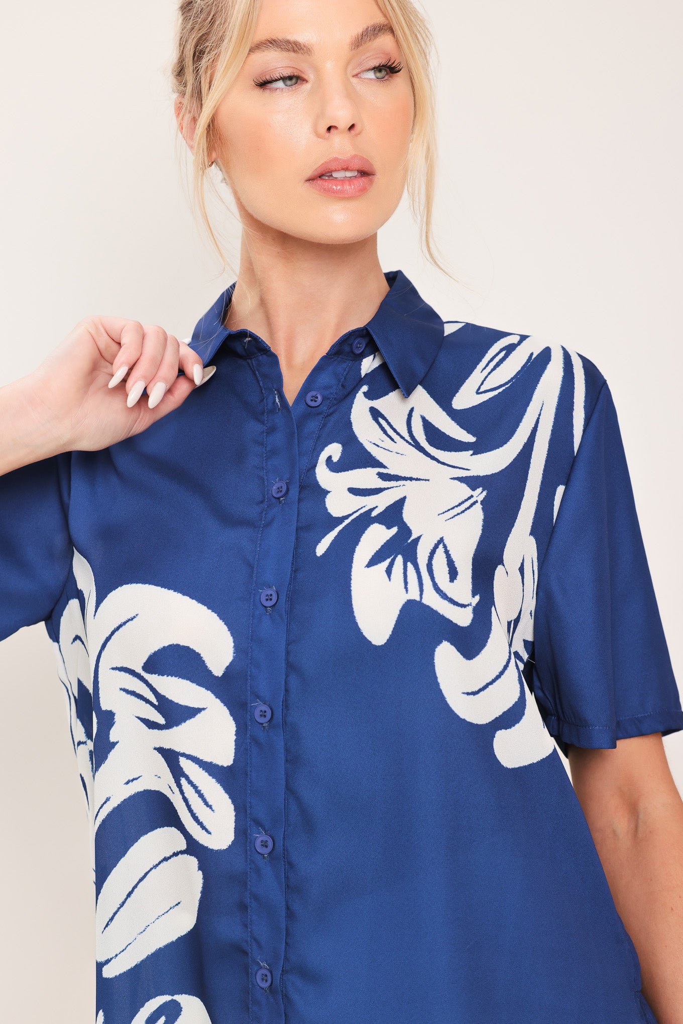 Woman wearing a navy blue with white floral print collared, short-sleeve button down top | Flying Tomato