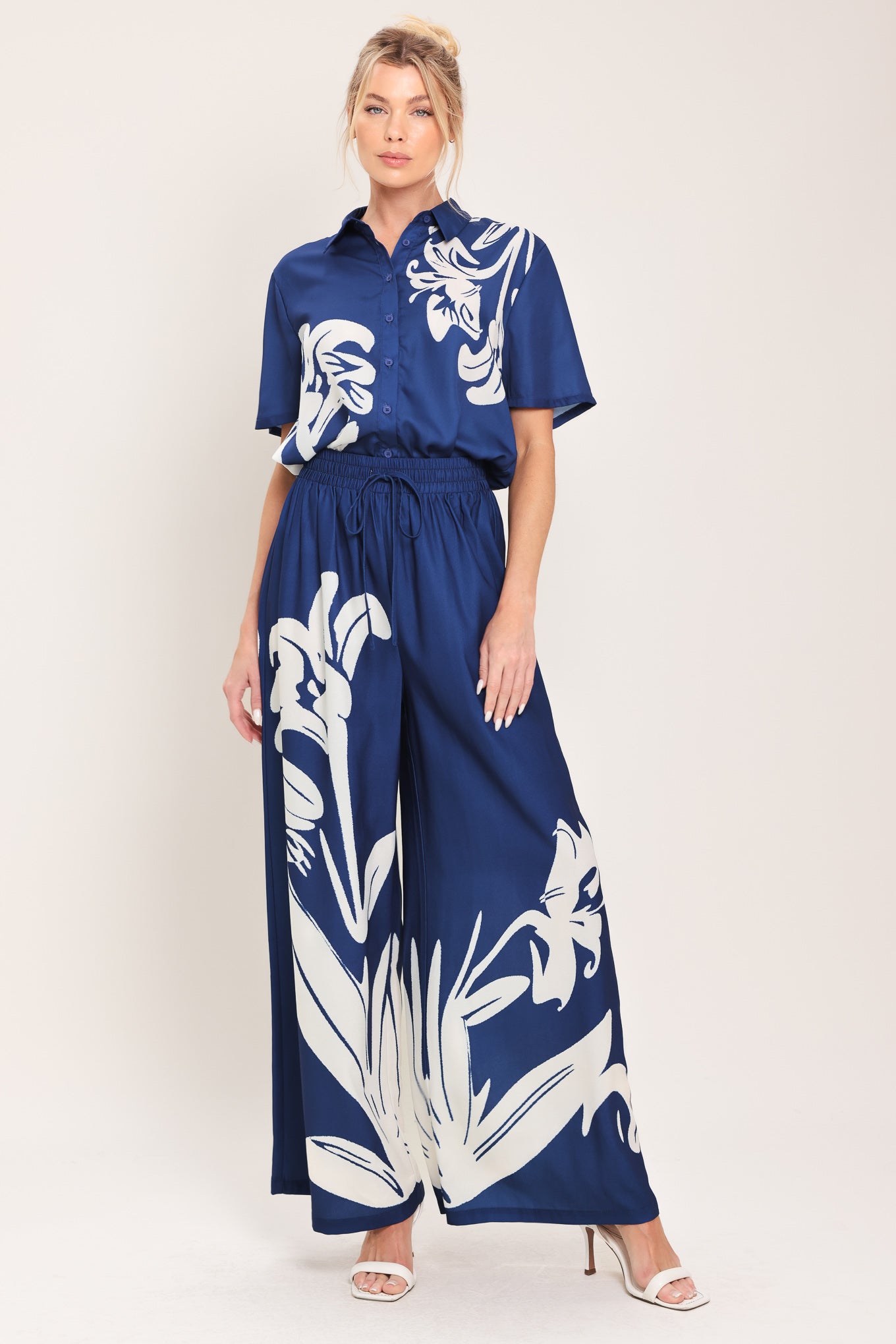 Woman wearing a navy blue with white floral print collared, short-sleeve button down top | Flying Tomato