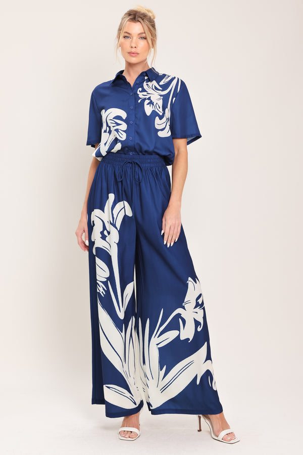Woman wearing a navy blue with white floral print collared, short-sleeve button down top | Flying Tomato