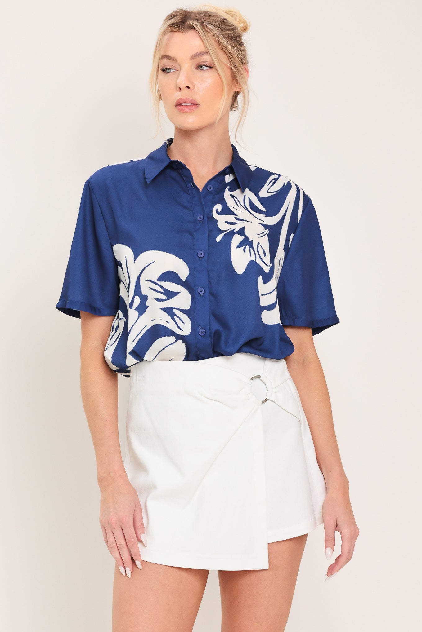 Woman wearing a navy blue with white floral print collared, short-sleeve button down top | Flying Tomato