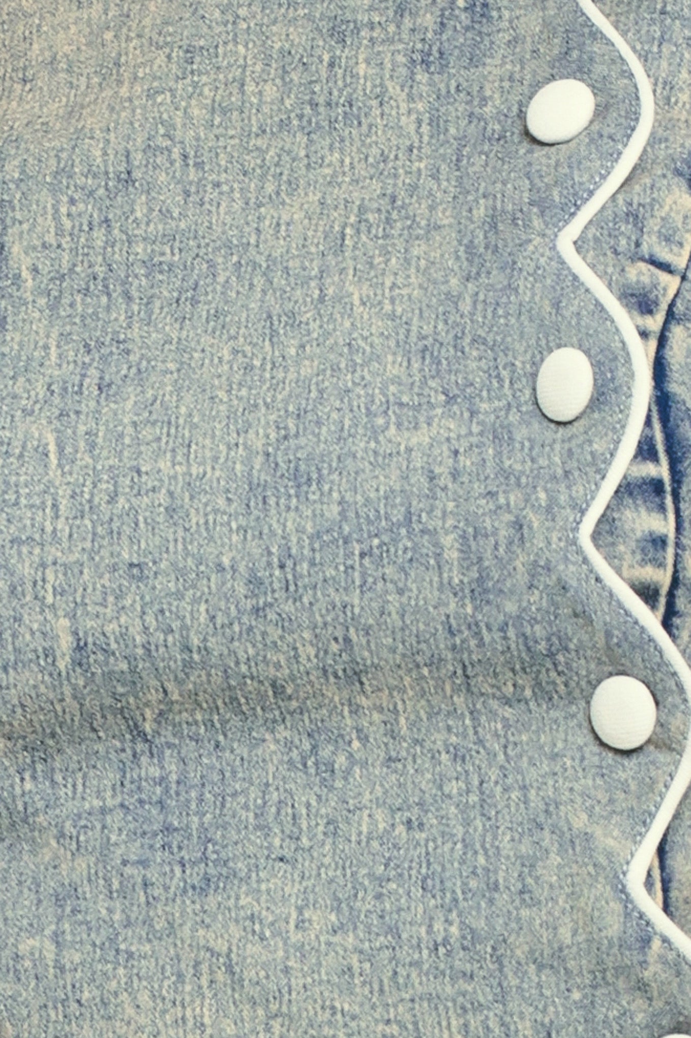 Close-up of blue denim fabric with button and scallop details | Flying Tomato