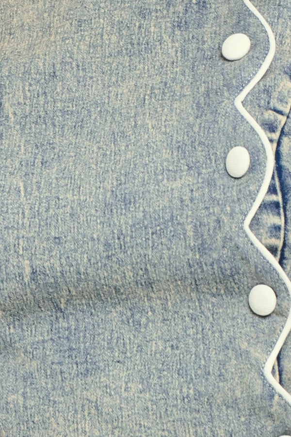 Close-up of blue denim fabric with button and scallop details | Flying Tomato