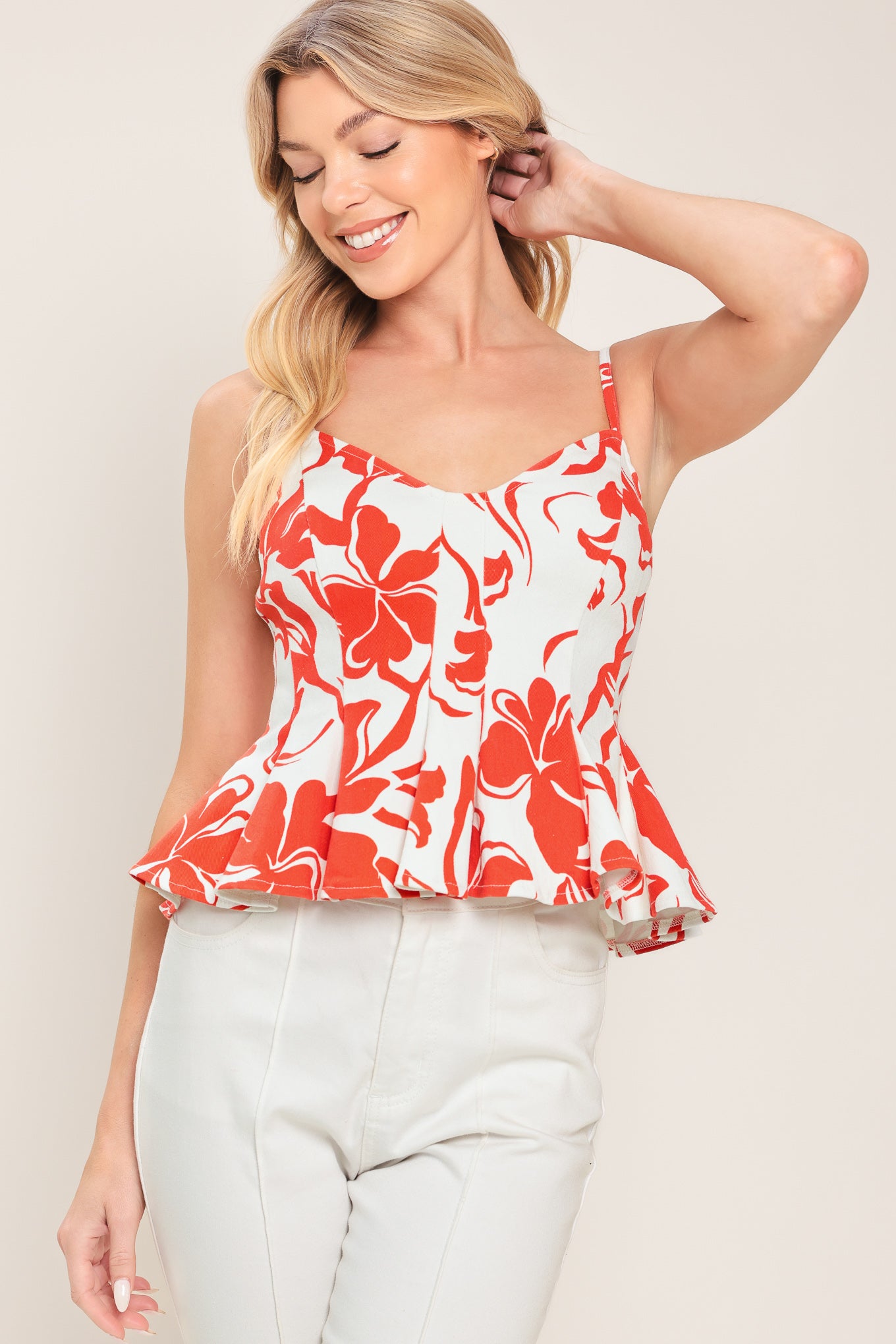 Woman wearing a red and white floral top with straps, peplum and back zipper closure | Flying Tomato