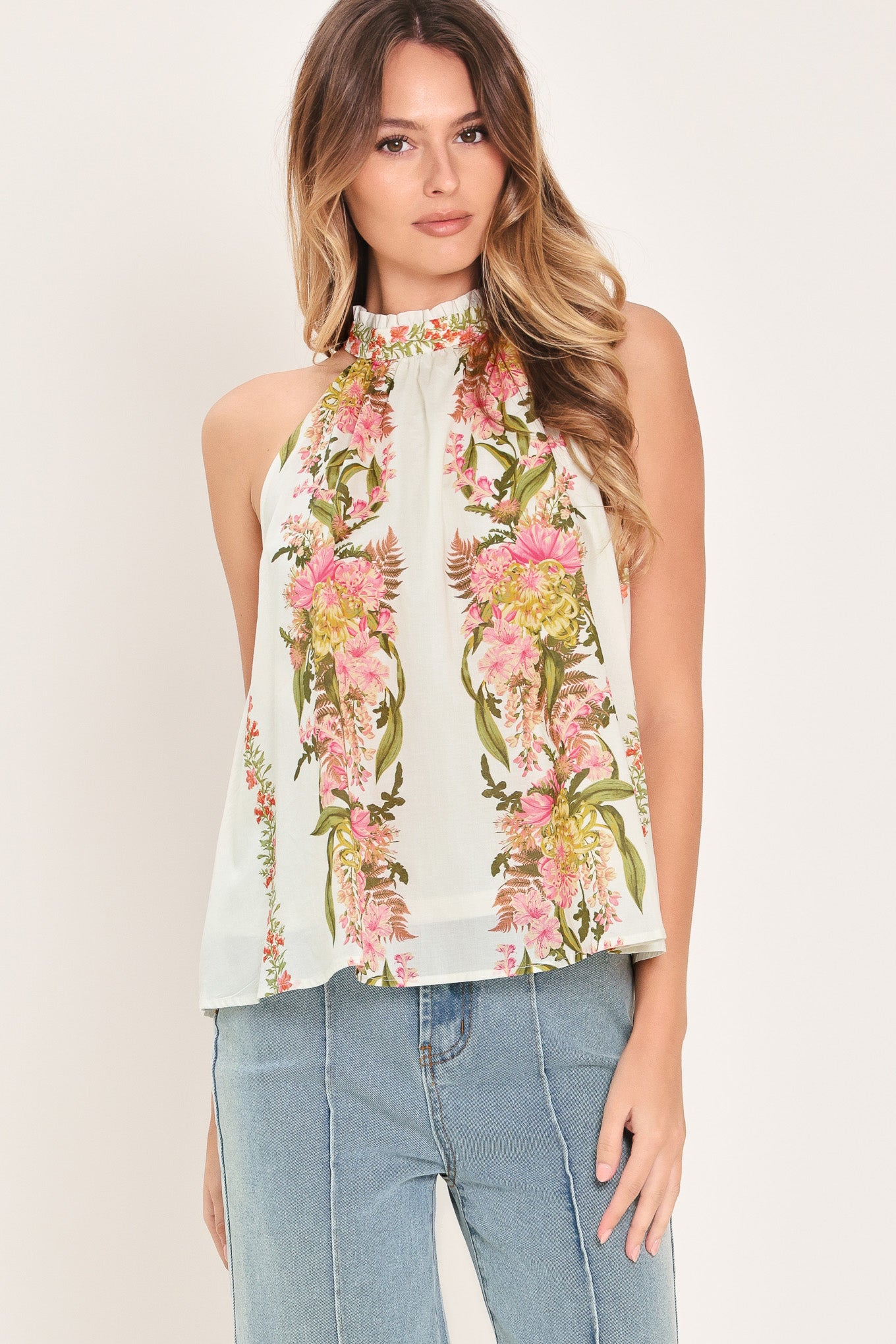 Woman wearing a floral sleeveless woven halter top with back neck button closure | Flying Tomato