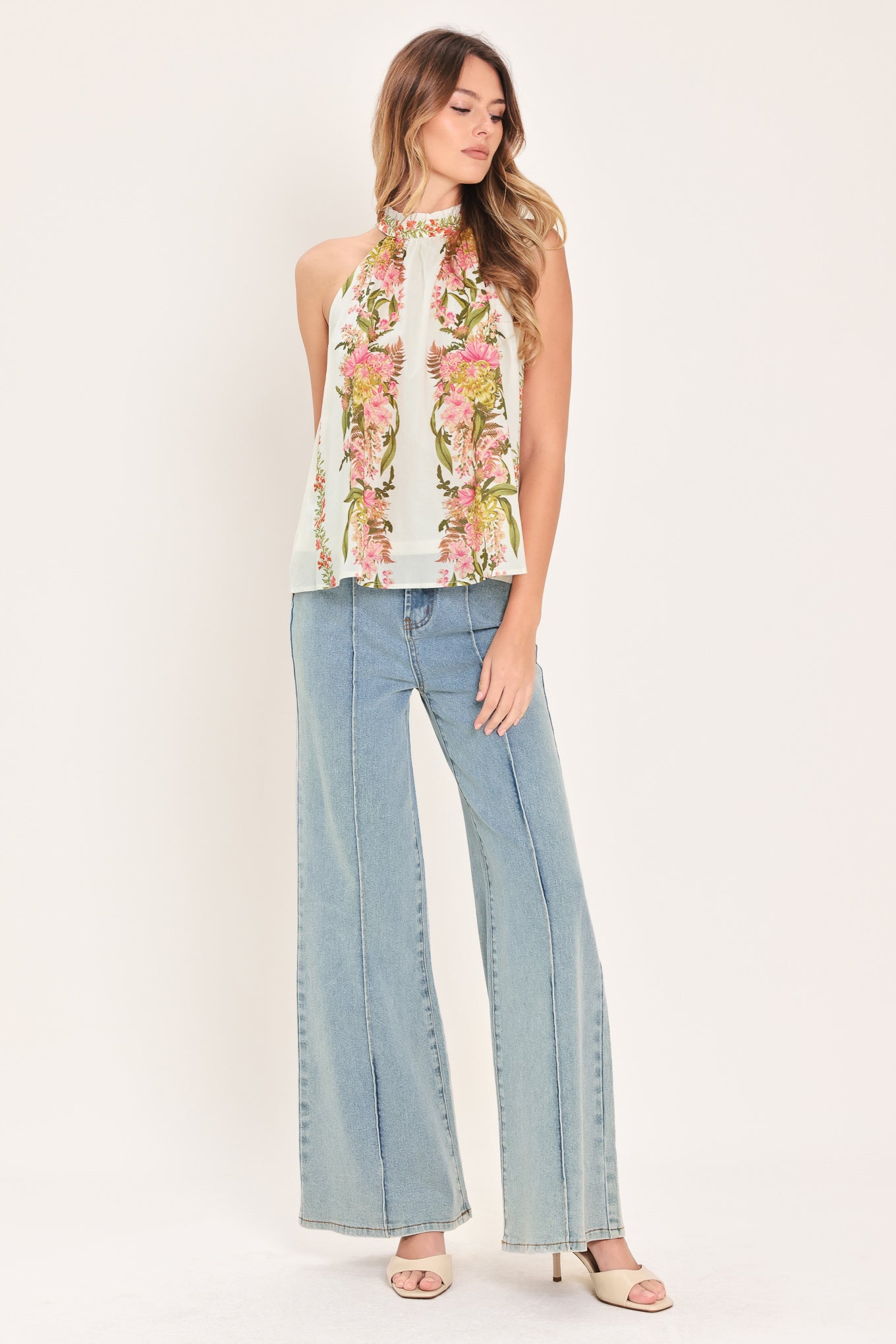 Woman wearing a floral sleeveless woven halter top with back neck button closure | Flying Tomato