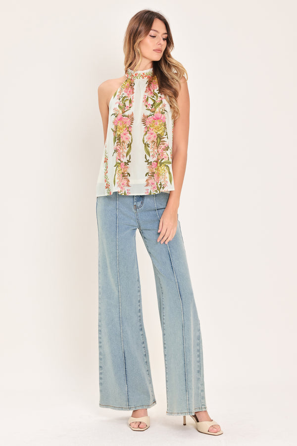 Woman wearing a floral sleeveless woven halter top with back neck button closure | Flying Tomato