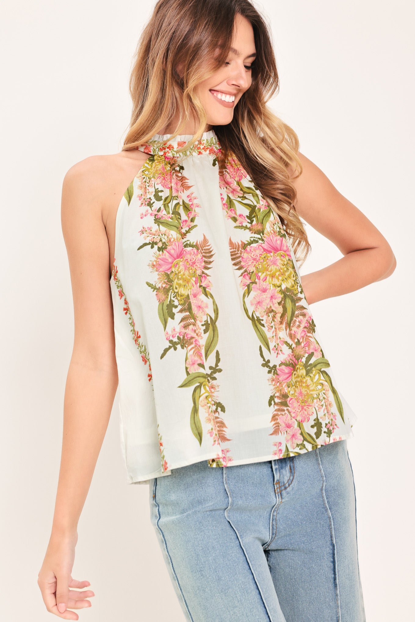 Woman wearing a floral sleeveless woven halter top with back neck button closure | Flying Tomato
