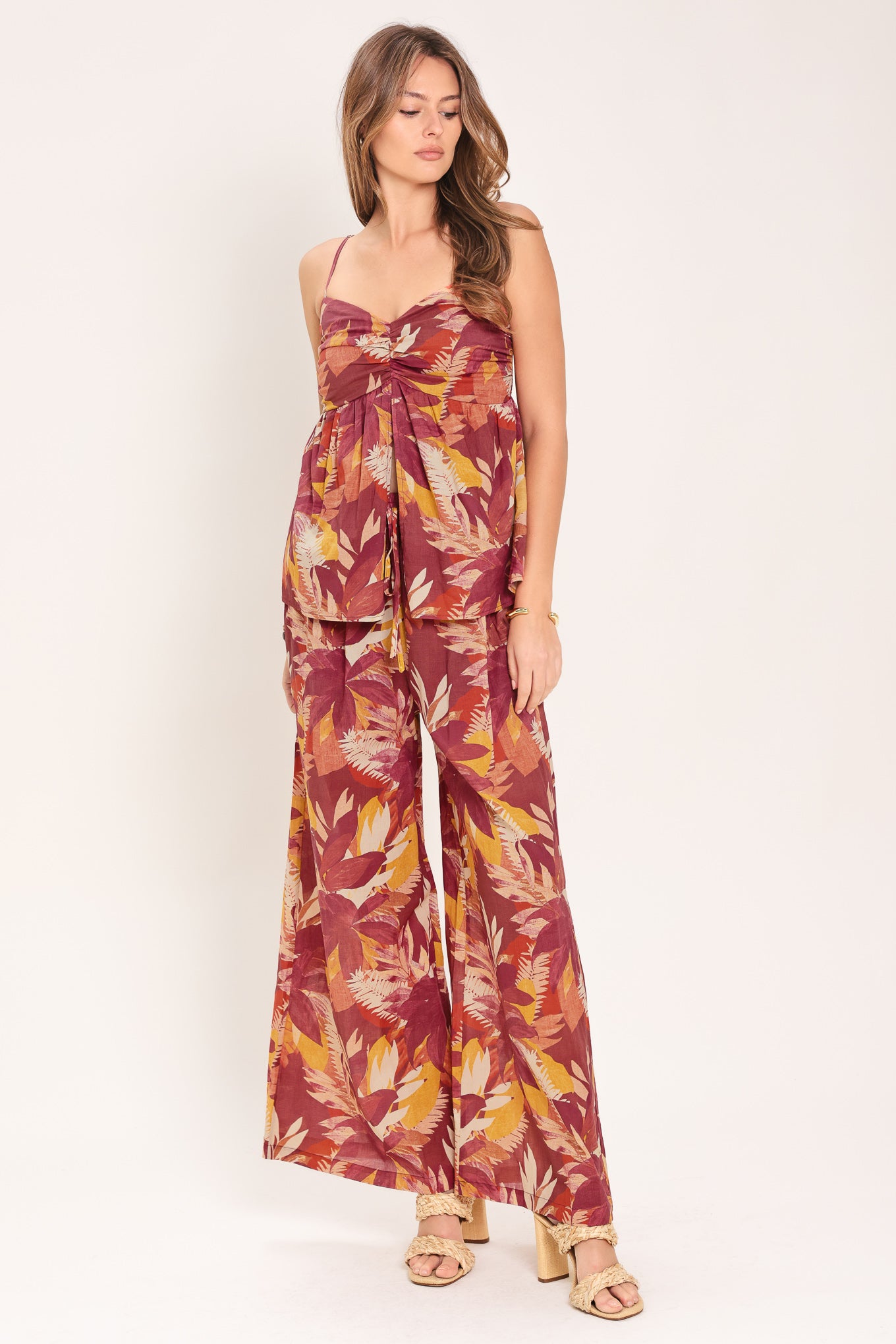 Woman wearing a burgundy printed woven top featuring cinched center, split front and smocked back bodice | Flying Tomato