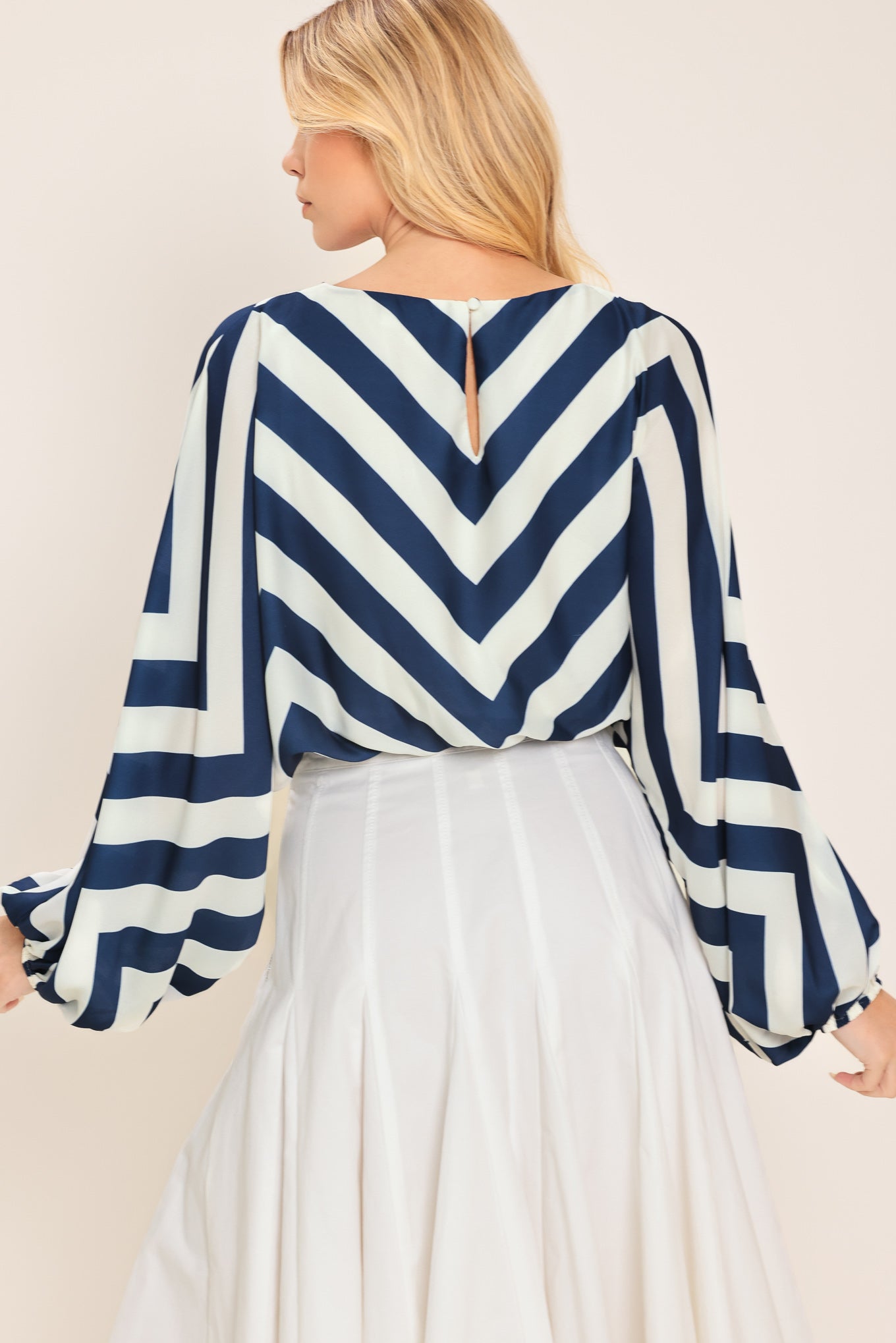 Woman wearing a navy and white chevron patterned top featuring wide neckline, dolman sleeve, elastic waist and back neck button closure | Flying Tomato