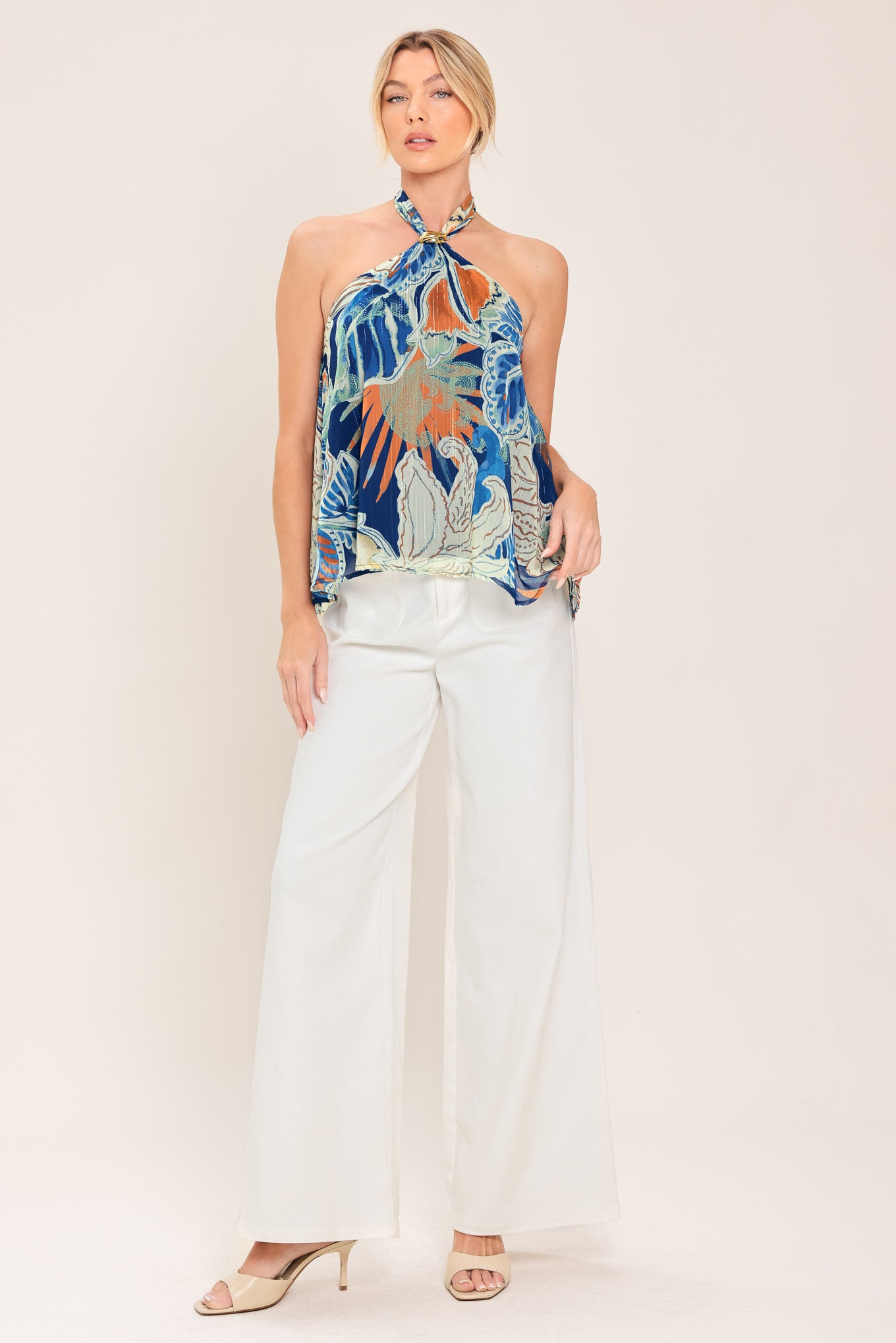 A woman wearing a halter-neck top with a tropical print in shades of blue, orange, and beige | Flying Tomato
