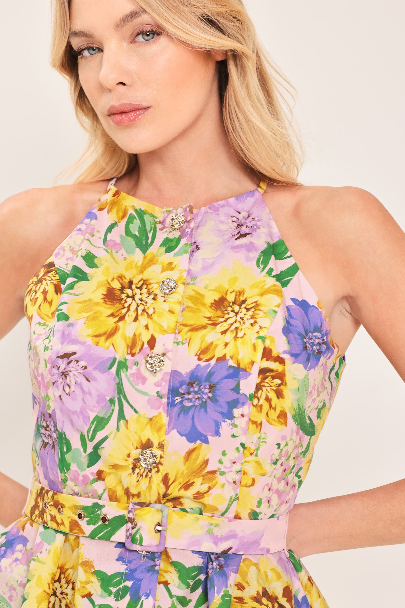 Woman wearing a yellow and purple floral top with front button down, self belt and peplum | Flying Tomato
