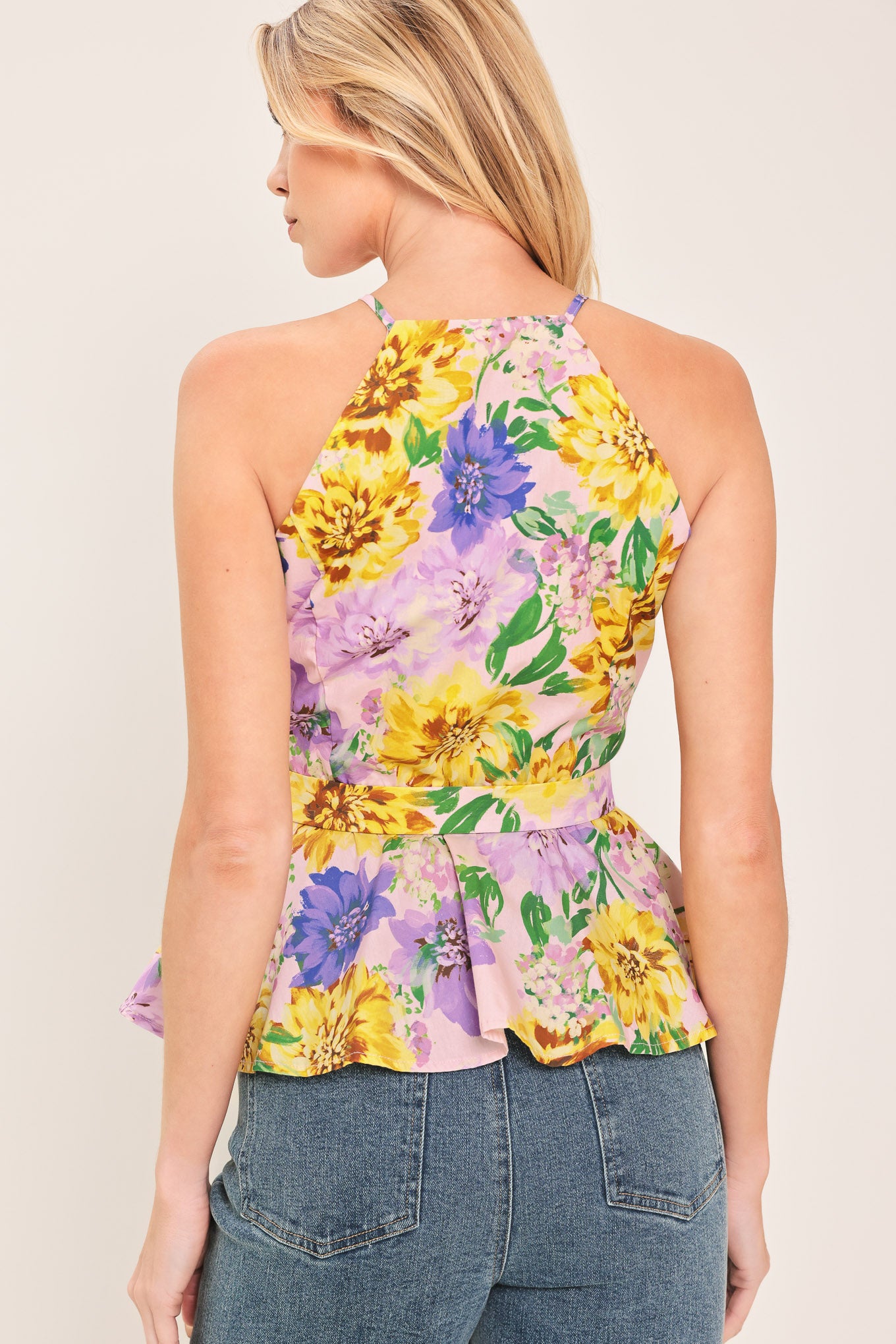 Woman wearing a yellow and purple floral top with front button down, self belt and peplum | Flying Tomato