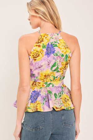 Woman wearing a yellow and purple floral top with front button down, self belt and peplum | Flying Tomato