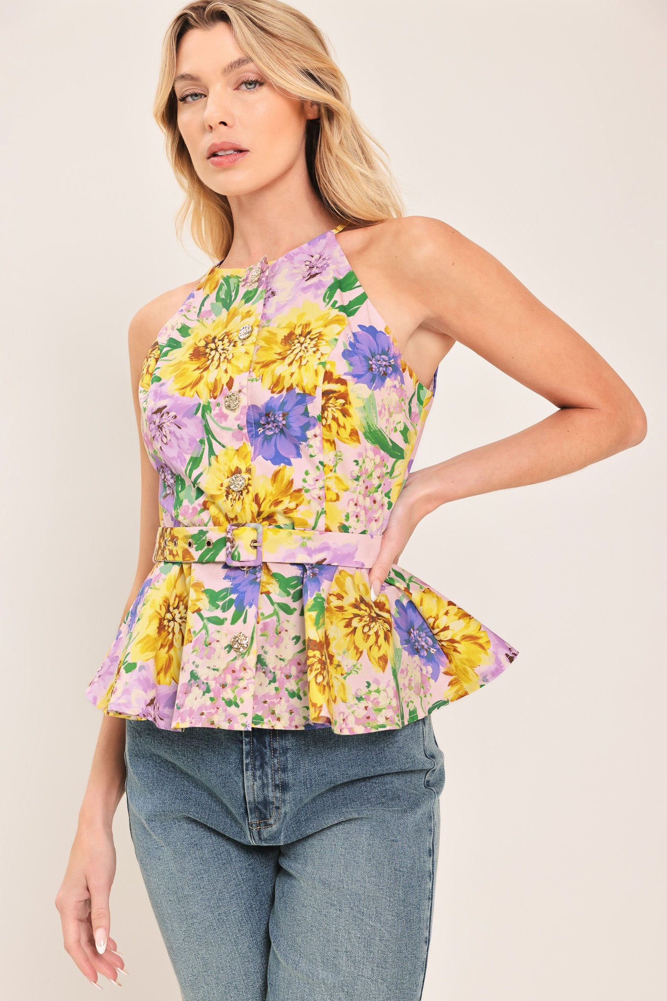 Woman wearing a yellow and purple floral top with front button down, self belt and peplum | Flying Tomato