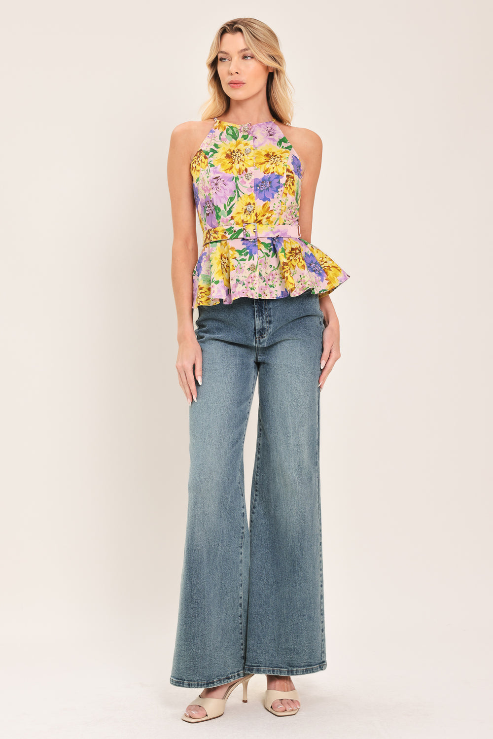 Woman wearing a yellow and purple floral top with front button down, self belt and peplum | Flying Tomato