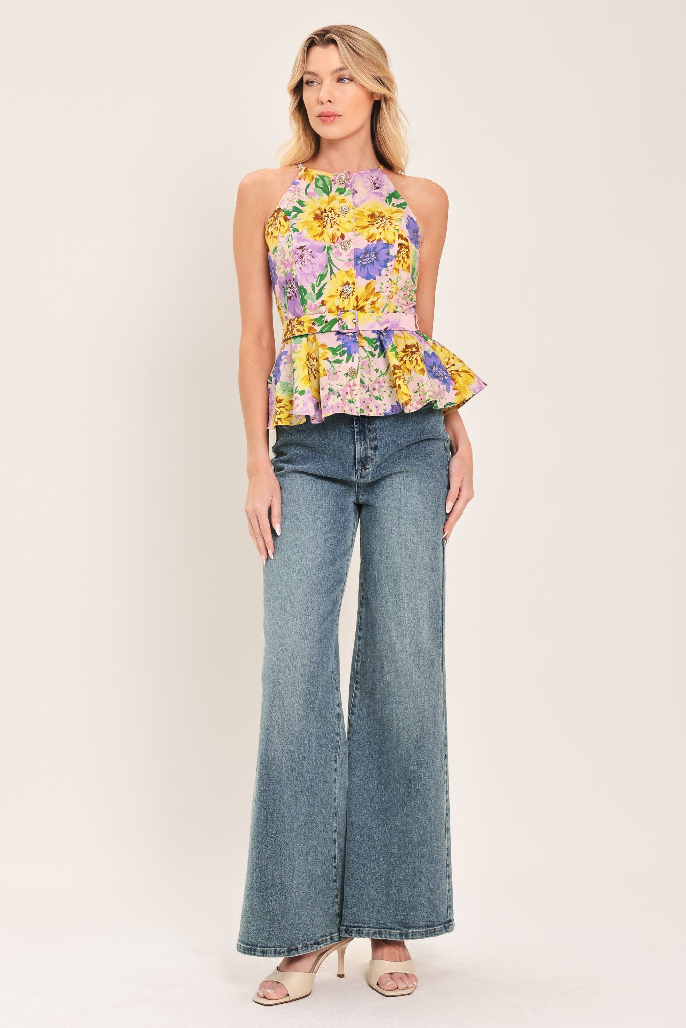 Woman wearing a yellow and purple floral top with front button down, self belt and peplum | Flying Tomato