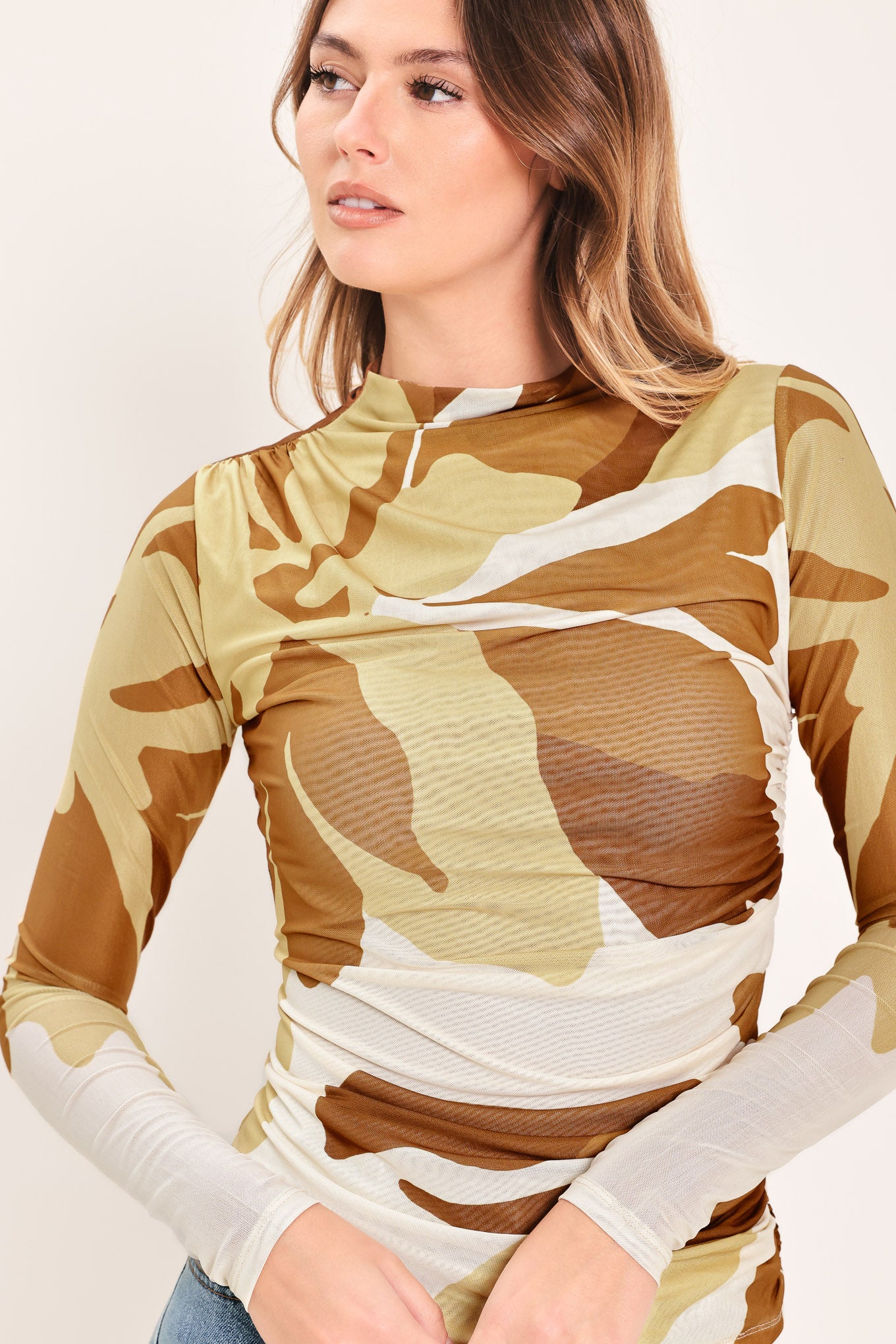 Woman wearing a multicolor brown, yellow, and ivory long-sleeve power mesh top with funnel neck and side shirring | Flying Tomato
