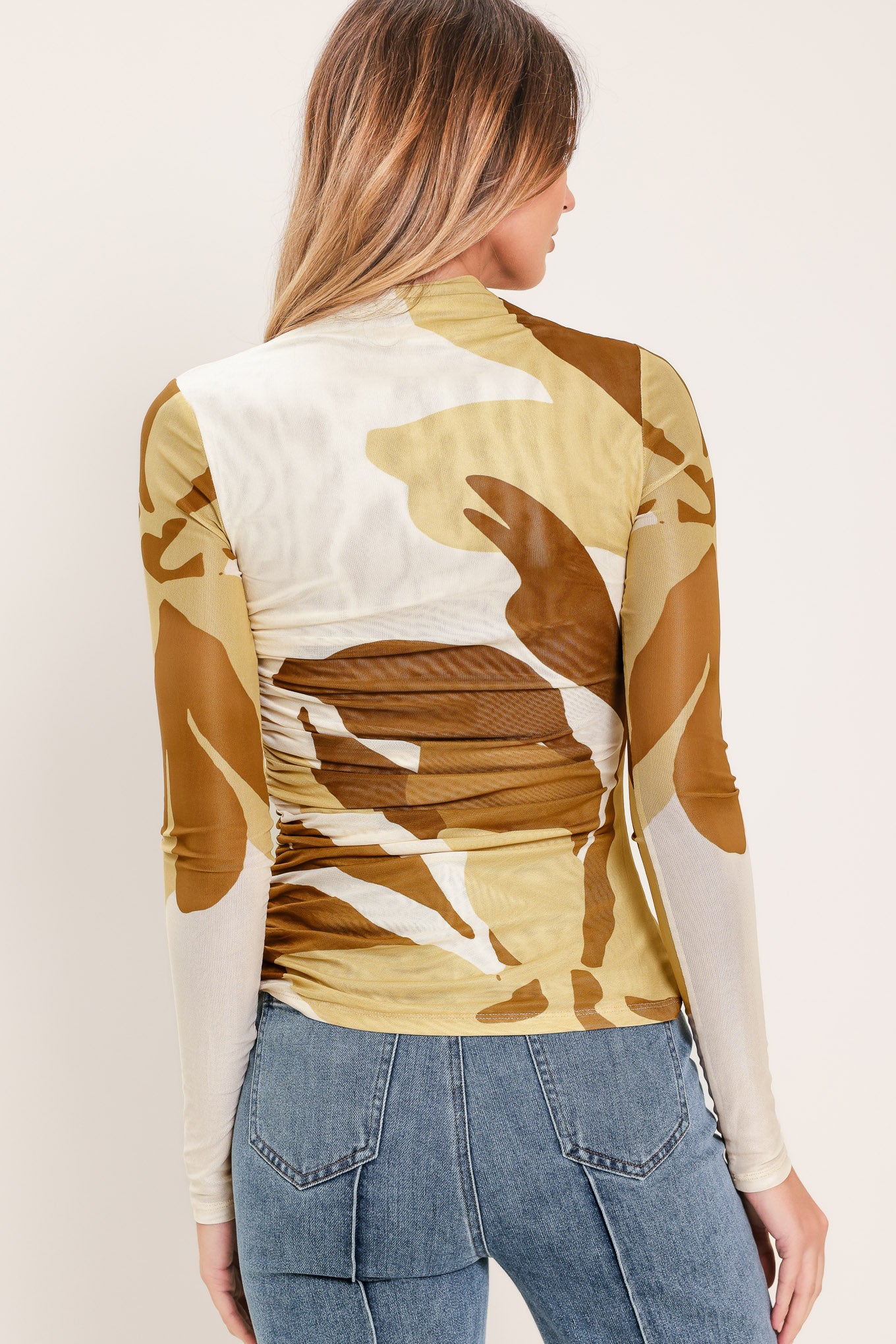 Woman wearing a multicolor brown, yellow, and ivory long-sleeve power mesh top with funnel neck and side shirring | Flying Tomato
