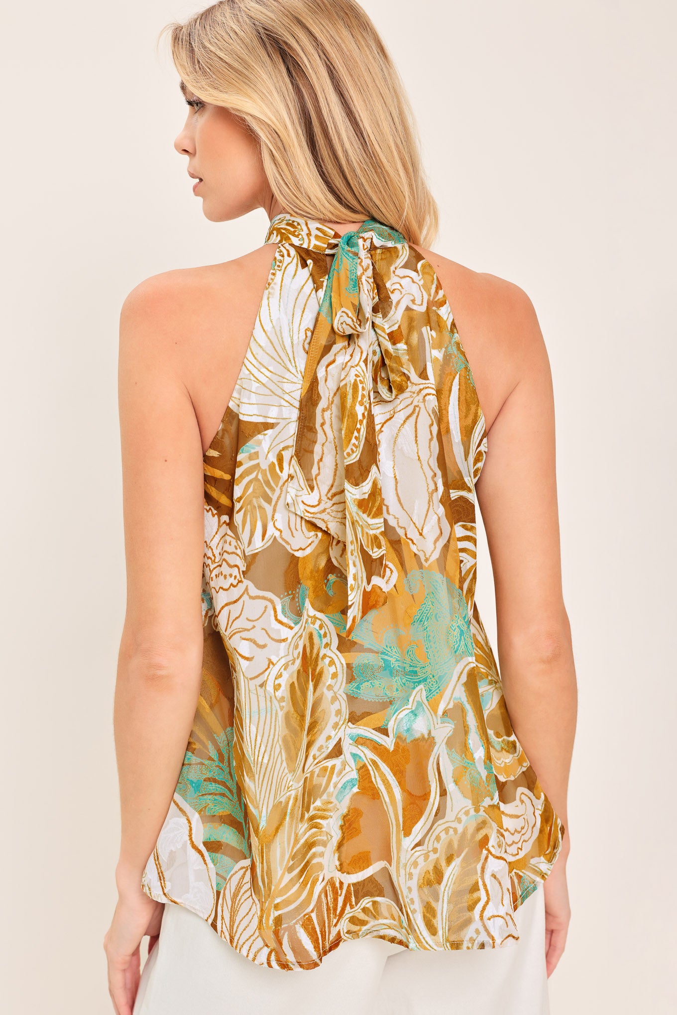 Woman wearing a sleeveless tropical floral jacquard printed top with halter neckline with back neck tie | Flying Tomato
