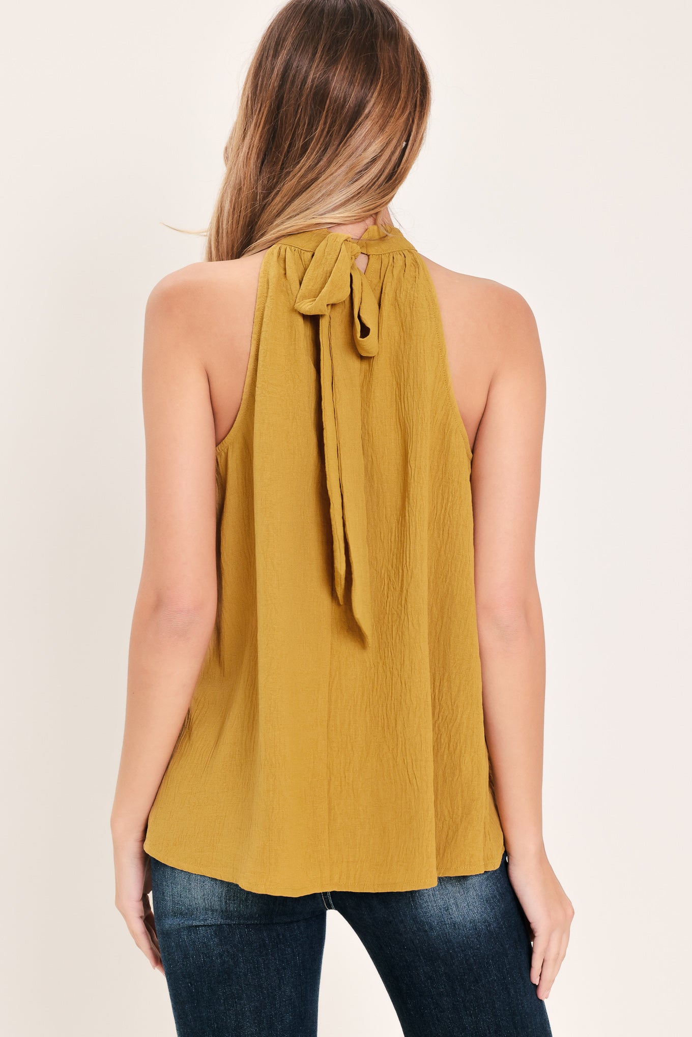 Woman wearing a mustard yellow sleeveless halter top | Flying Tomato