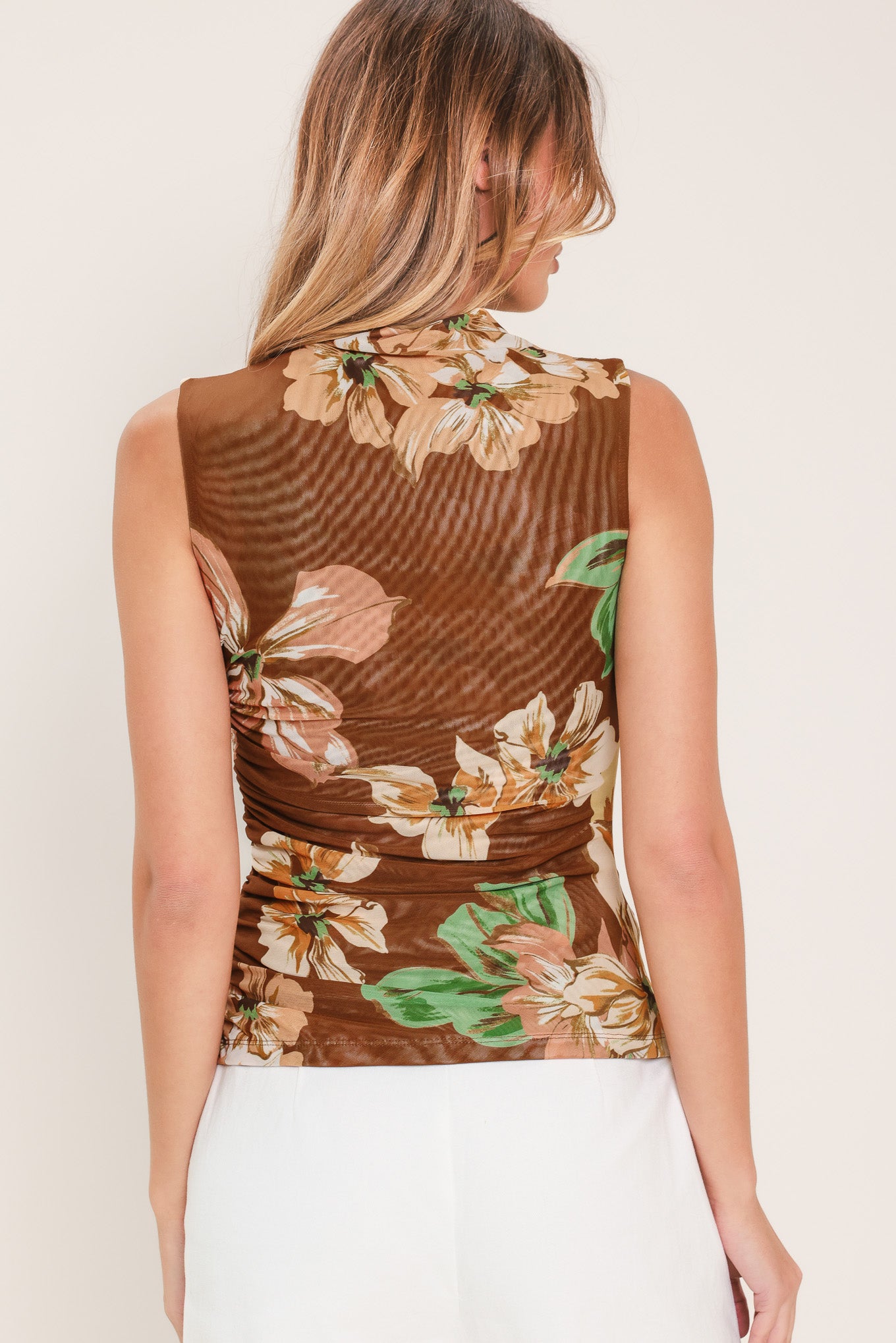 Woman wearing a brown floral sleeveless power mesh with funnel neck and side shirring | Flying Tomato