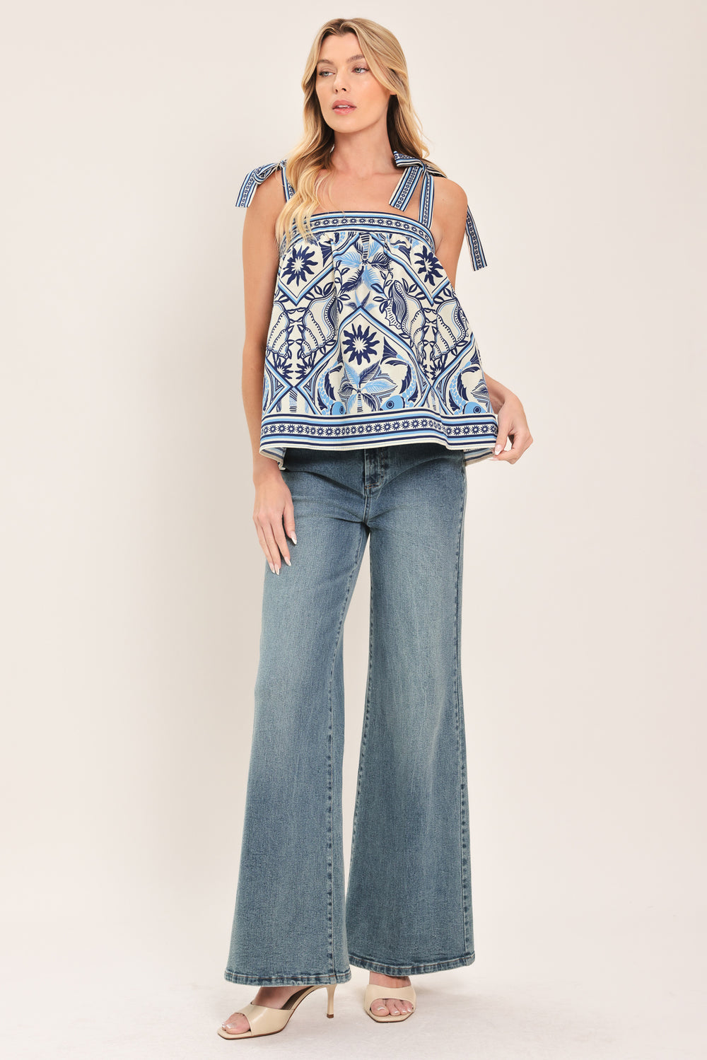 Woman wearing a blue and white patterned top with shoulder ties and smocked back band | Flying Tomato