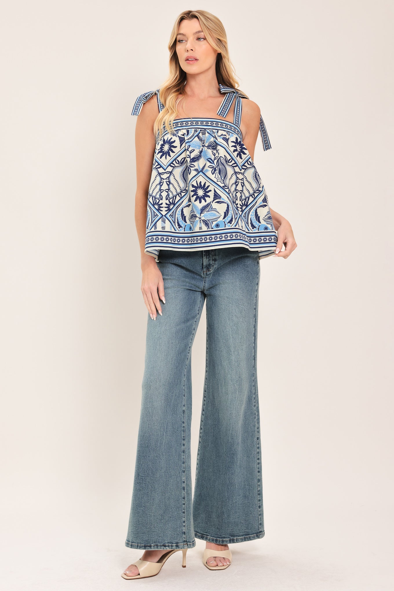 Woman wearing a blue and white patterned top with shoulder ties and smocked back band | Flying Tomato