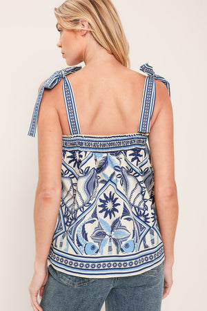Woman wearing a blue and white patterned top with shoulder ties and smocked back band | Flying Tomato