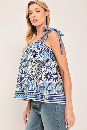 Woman wearing a blue and white patterned top with shoulder ties and smocked back band | Flying Tomato