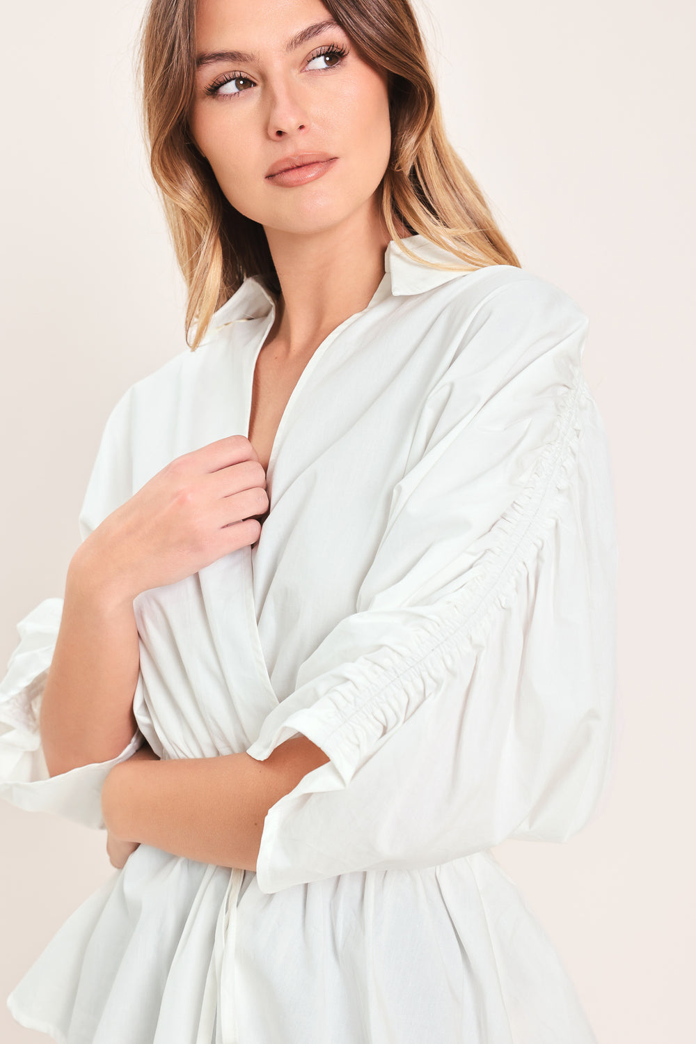 Woman wearing a white top featuring collar, surplice neckline, elastic waist with tie, elbow sleeve with shirring and peplum | Flying Tomato