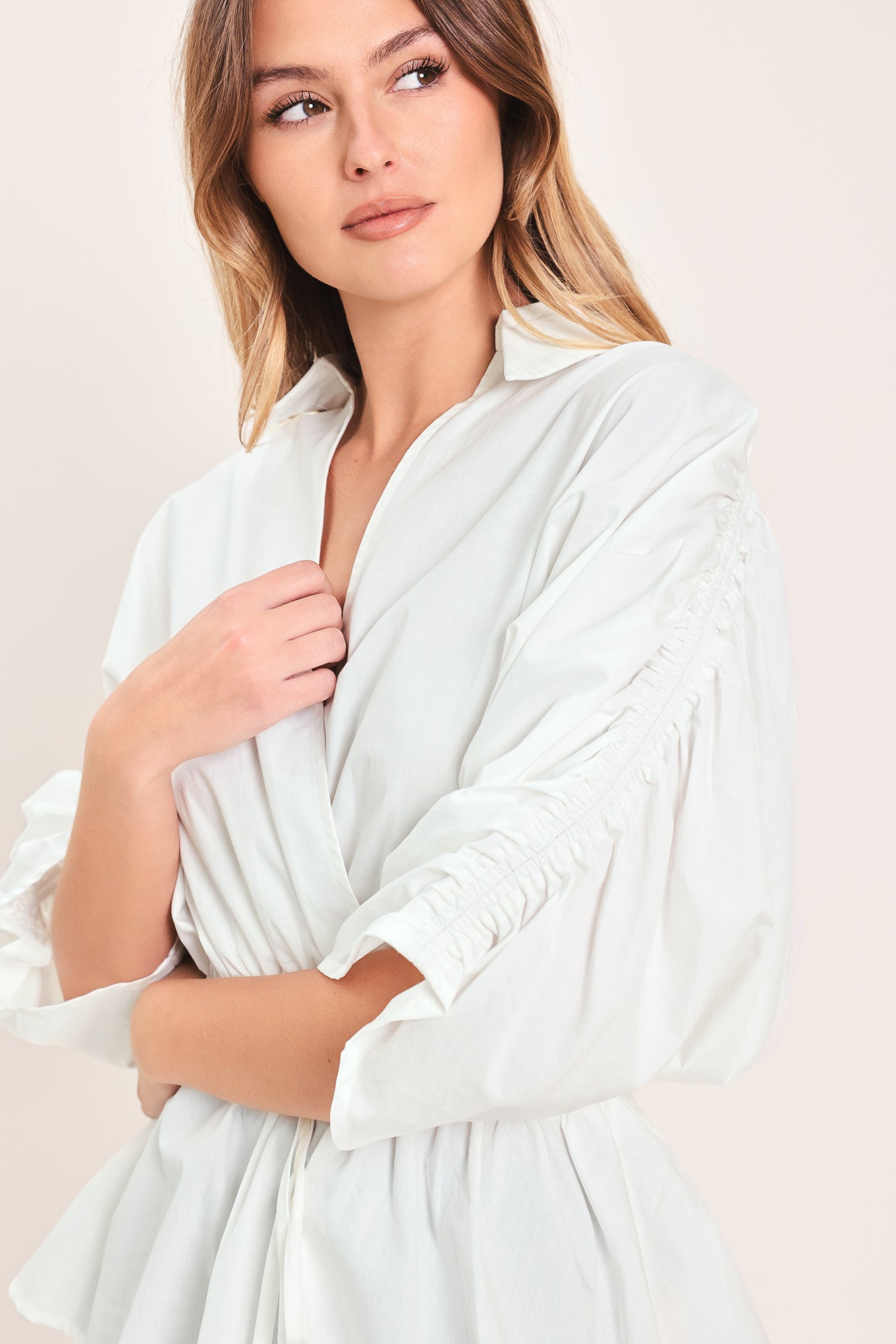 Woman wearing a white top featuring collar, surplice neckline, elastic waist with tie, elbow sleeve with shirring and peplum | Flying Tomato
