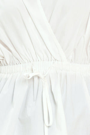 Woman wearing a white top featuring collar, surplice neckline, elastic waist with tie, elbow sleeve with shirring and peplum | Flying Tomato