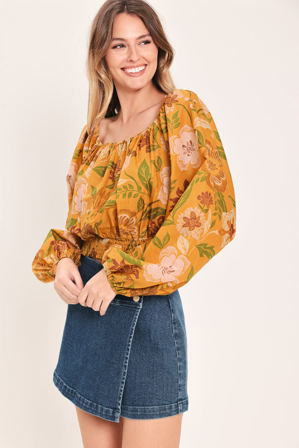 Woman wearing a yellow floral printed blouse featuring square neckline, long sleeve and smocked waistband | Flying Tomato
