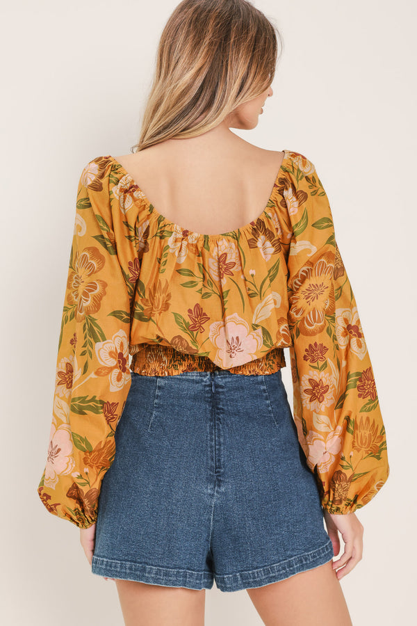 Woman wearing a yellow floral printed blouse featuring square neckline, long sleeve and smocked waistband | Flying Tomato