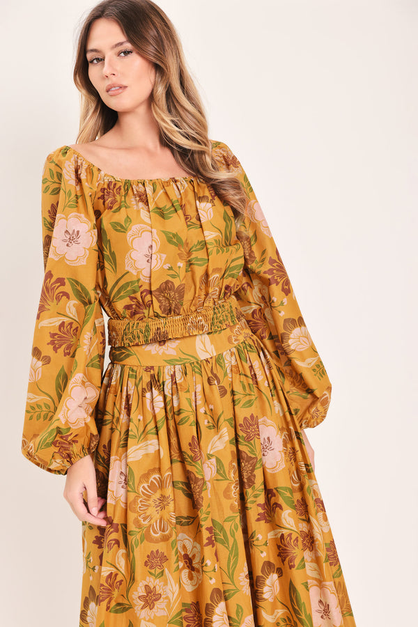 Woman wearing a yellow floral printed blouse featuring square neckline, long sleeve and smocked waistband | Flying Tomato