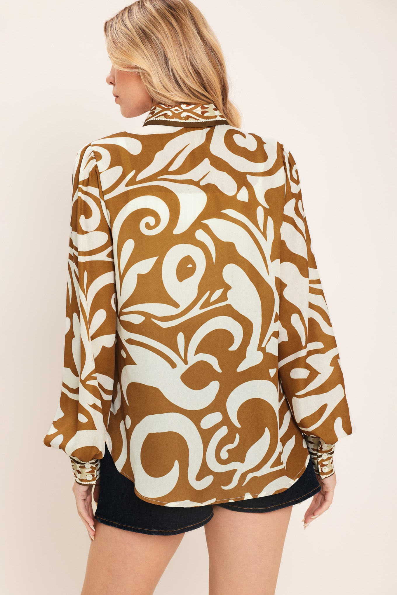 Woman wearing a brown and beige patterned collared blouse with buttons | Flying Tomato
