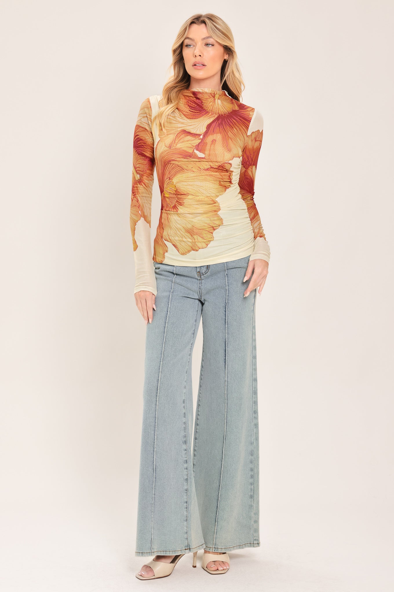 A woman wearing a long-sleeve mock neck power mesh top with a orange and ivory abstract leaf pattern | Flying Tomato