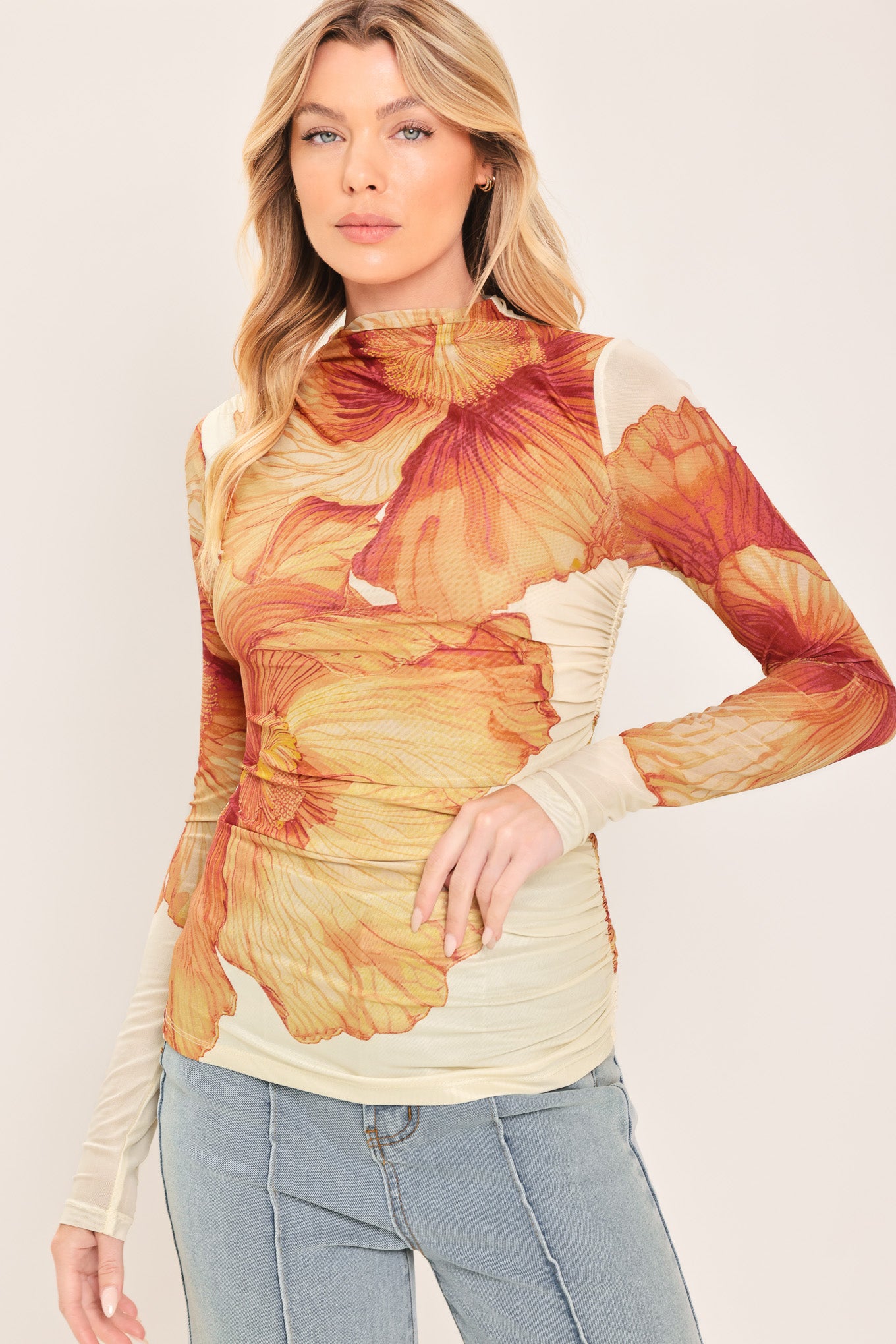 A woman wearing a long-sleeve mock neck power mesh top with a orange and ivory abstract leaf pattern | Flying Tomato