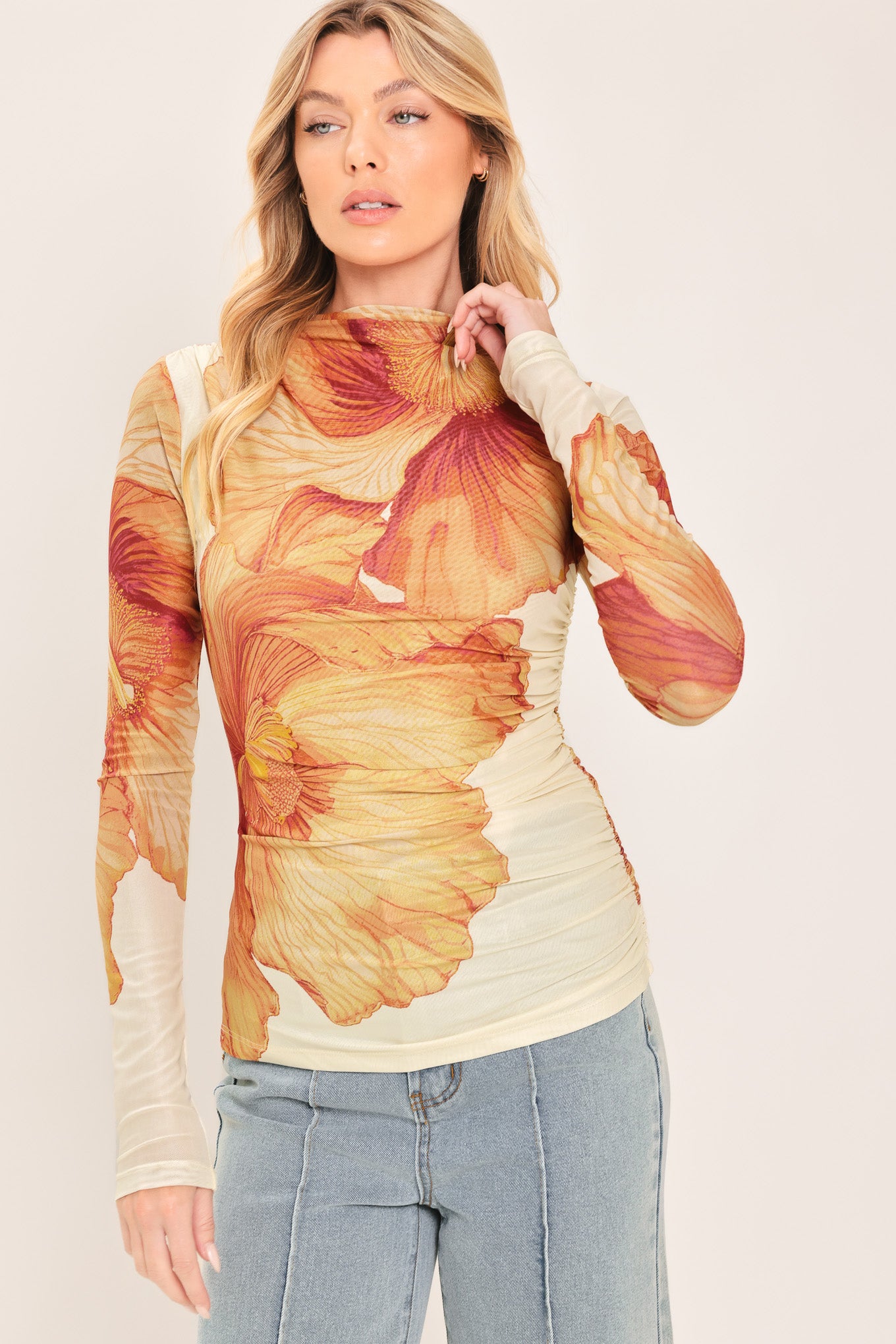 A woman wearing a long-sleeve mock neck power mesh top with a orange and ivory abstract leaf pattern | Flying Tomato