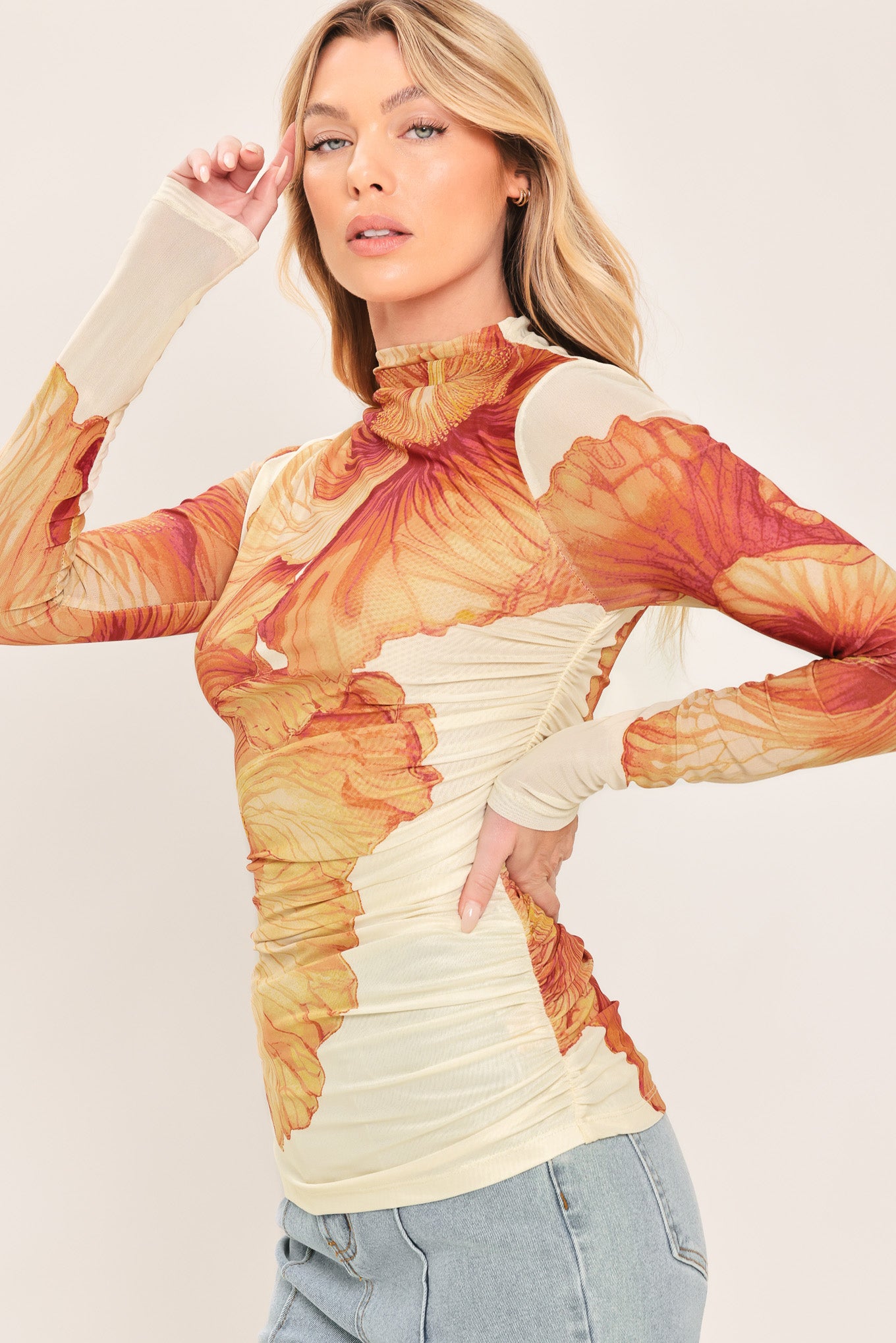 A woman wearing a long-sleeve mock neck power mesh top with a orange and ivory abstract leaf pattern | Flying Tomato
