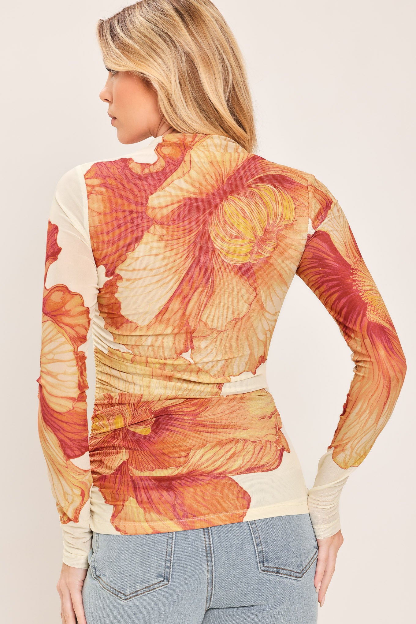A woman wearing a long-sleeve mock neck power mesh top with a orange and ivory abstract leaf pattern | Flying Tomato