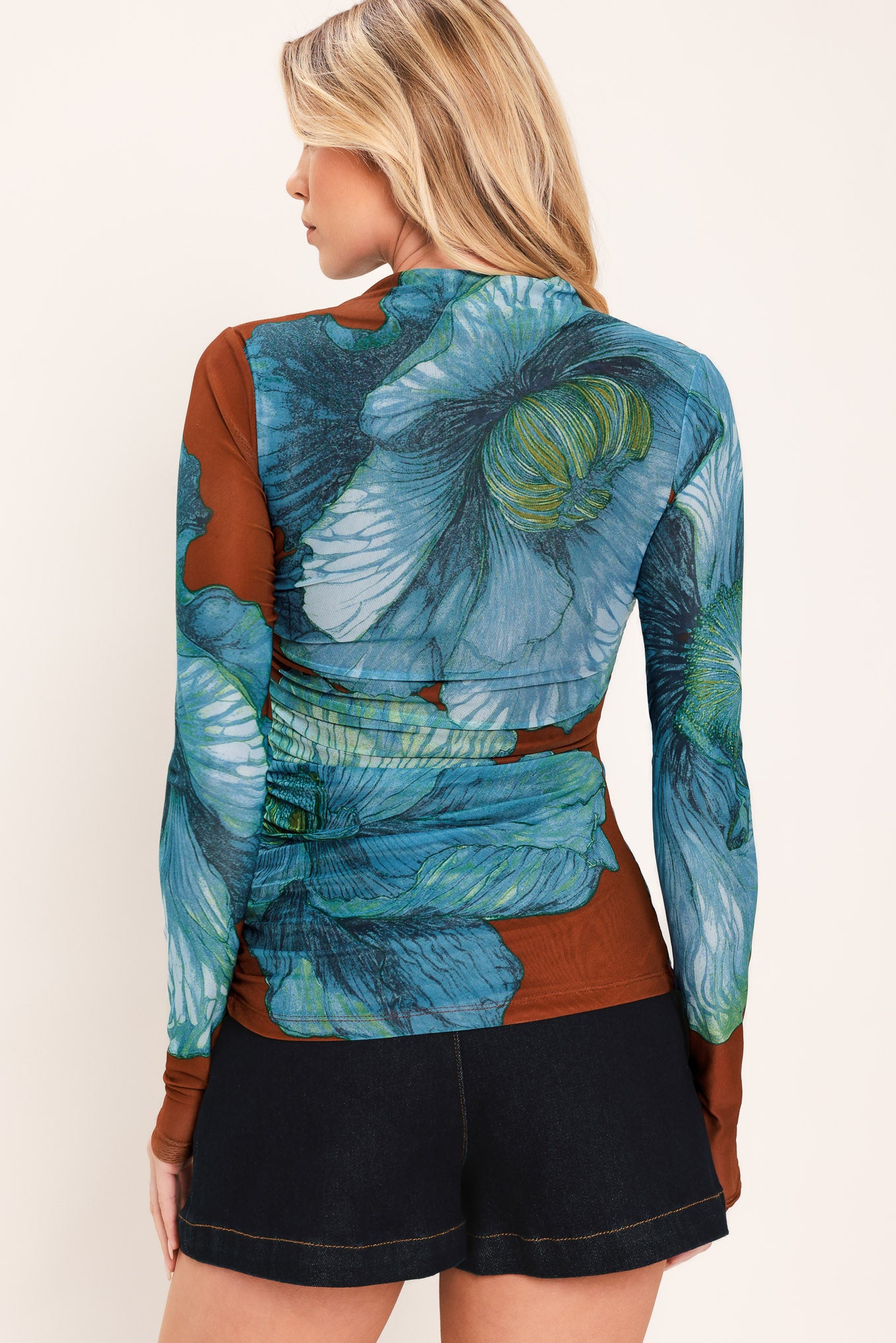 A woman wearing a long-sleeve mock neck power mesh top with a teal blue and green abstract leaf pattern | Flying Tomato