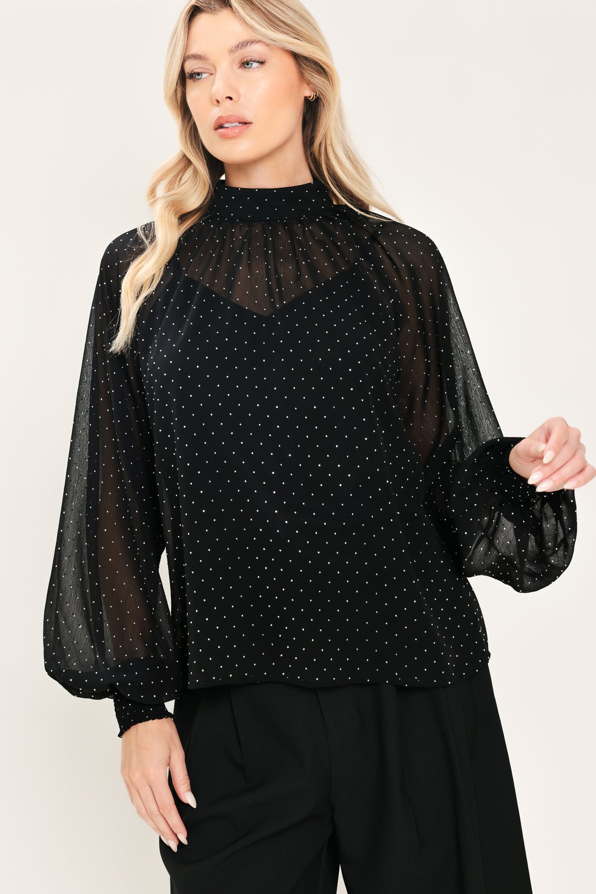 Woman wearing a long sleeve, mock neck, black top with small rhinestones | Flying Tomato