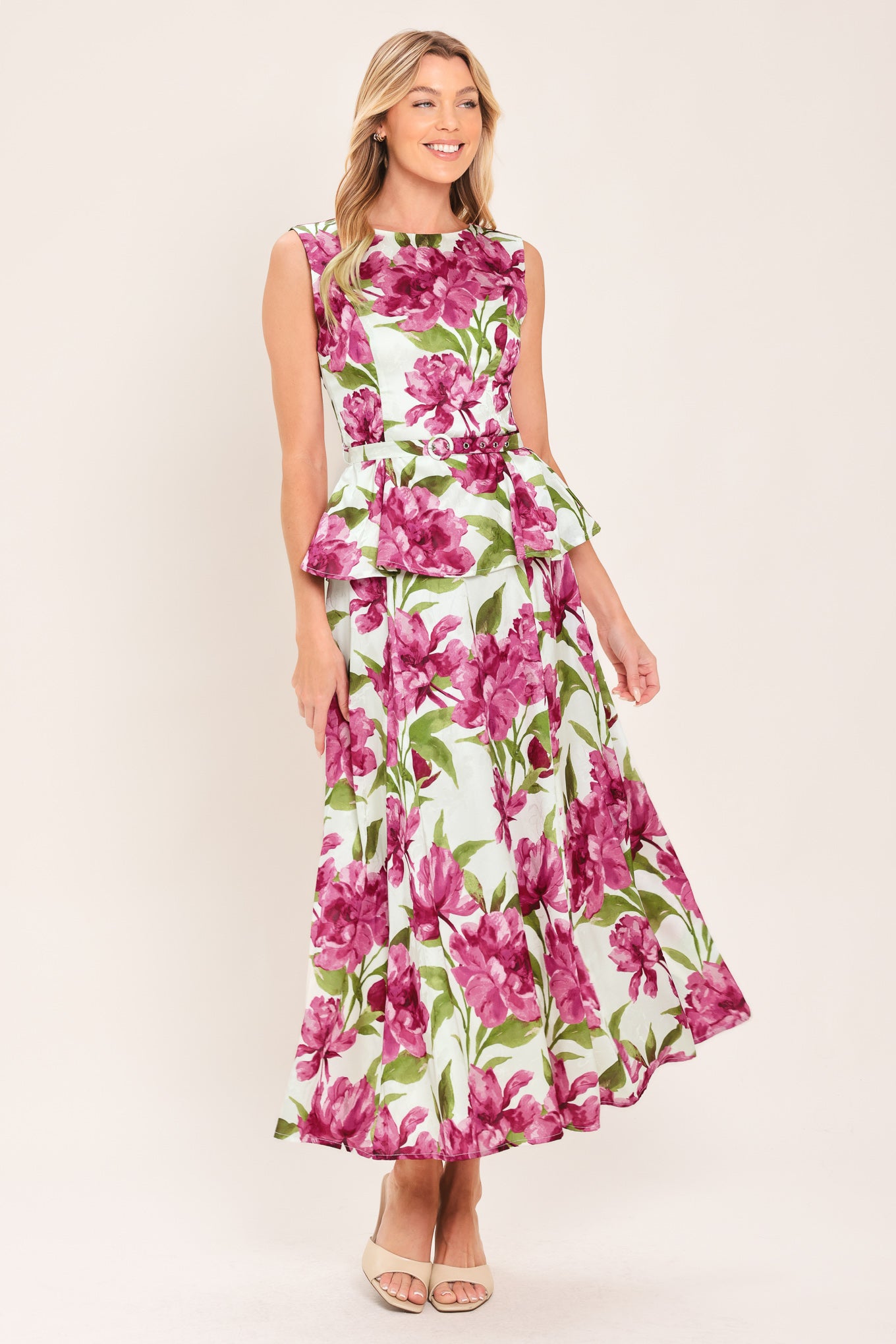 A woman wearing a sleeveless white peplum top with a vibrant pink and green floral print | Flying Tomato