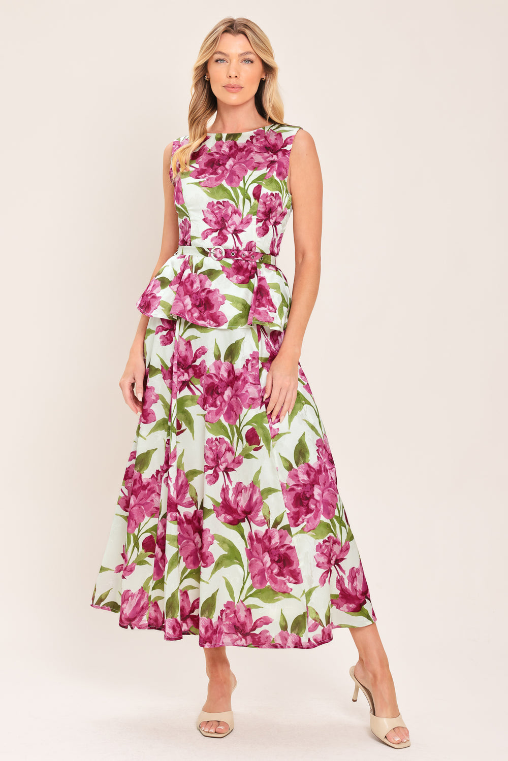 A woman wearing a sleeveless white peplum top with a vibrant pink and green floral print | Flying Tomato