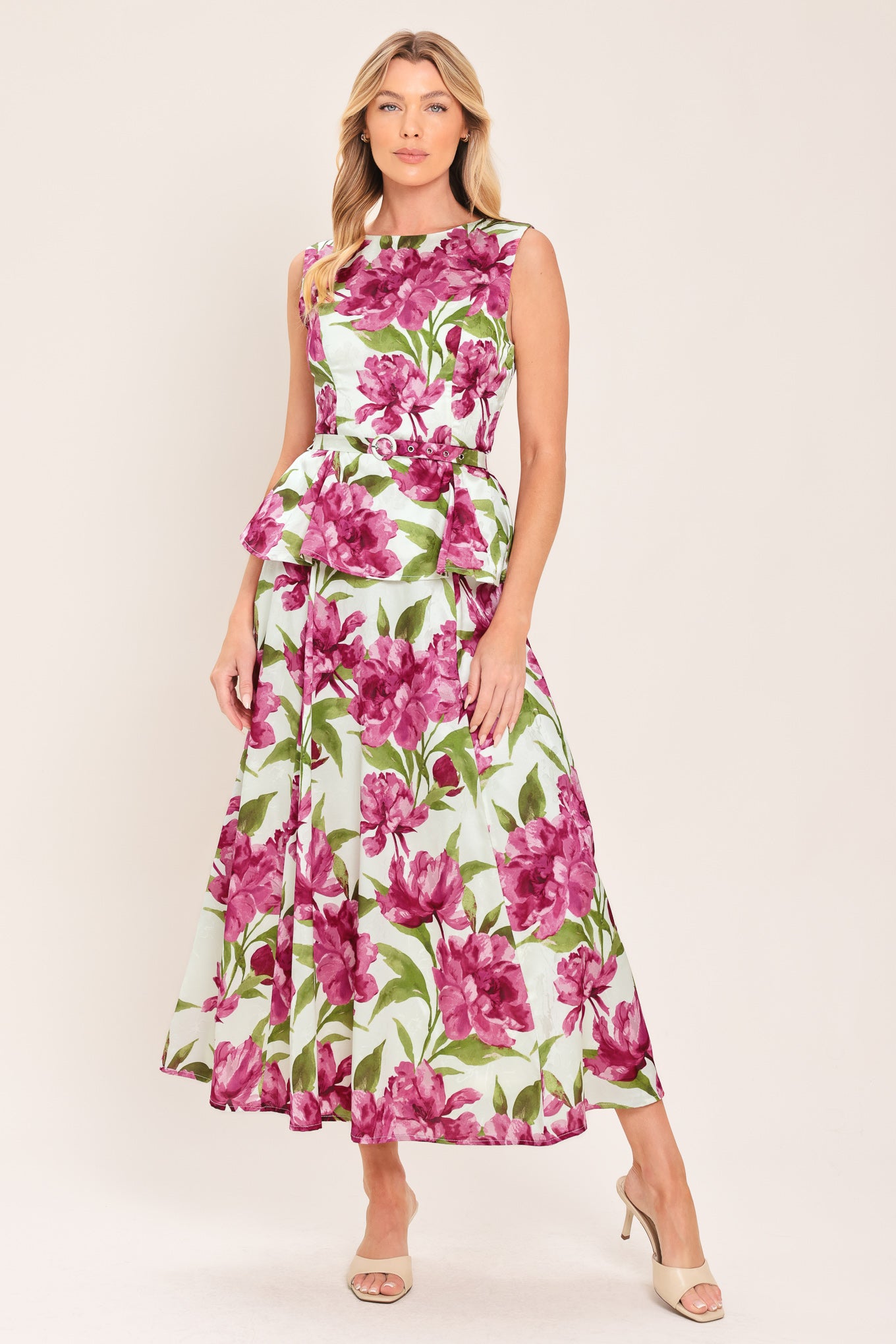 A woman wearing a sleeveless white peplum top with a vibrant pink and green floral print | Flying Tomato