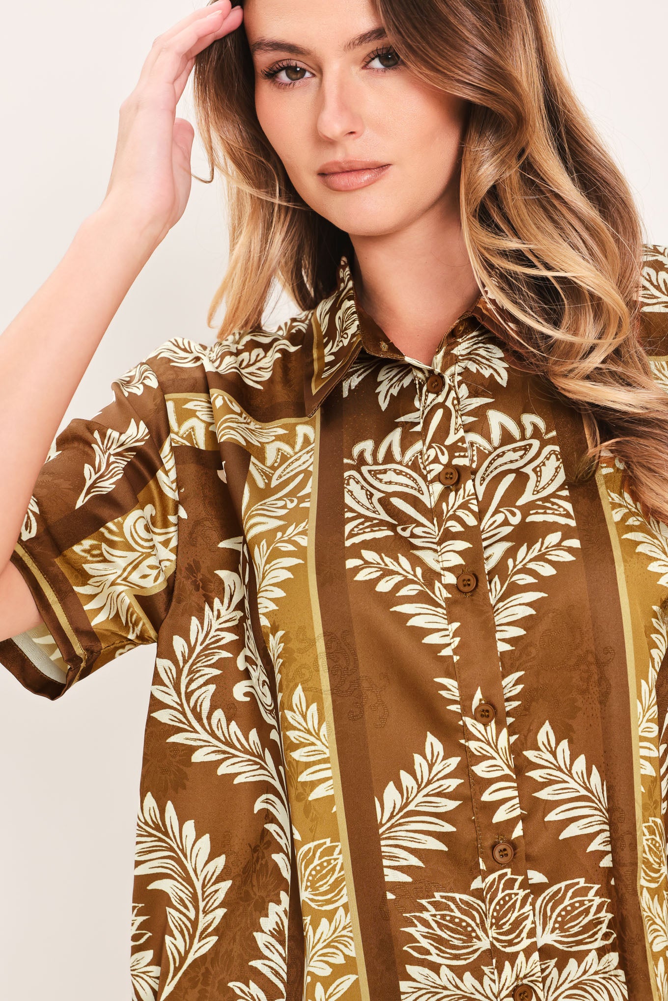 Woman wearing a brown floral patterned button down top | Flying Tomato