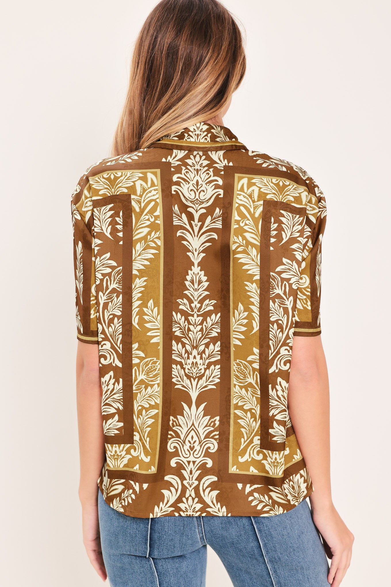 Woman wearing a brown floral patterned button down top | Flying Tomato